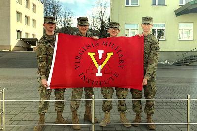 Four cadets hold up a VMI flag in Lithuania